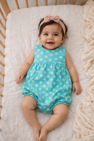 Baby wearing ocean blue romper while in crib