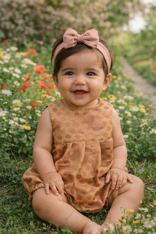 Baby wearing blush and gold romper