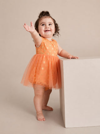 Child in an orange dress standing on a beige background